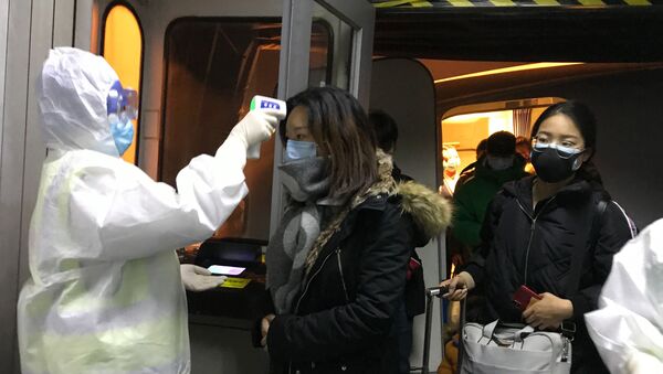 Медицинские работники в защитных костюмах проверяют температуру тела пассажиров, прибывающих из города Ухань в аэропорту Пекина, Китай - Sputnik 日本