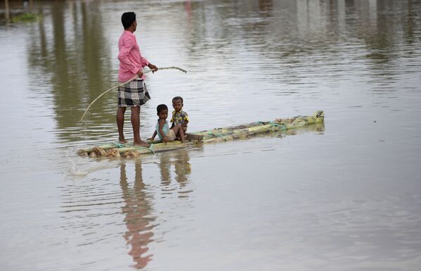 インド北東部、アッサム州の浸水被害に見舞われた村で、子どもを乗せていかだを漕ぐ男性（2020年7月14日） - Sputnik 日本