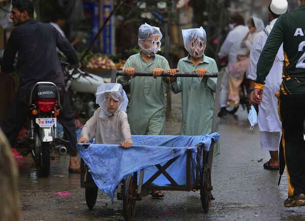 7月12日、パキスタンのペシャーワルで、ビニール袋を被って台車を押す子どもたち - Sputnik 日本