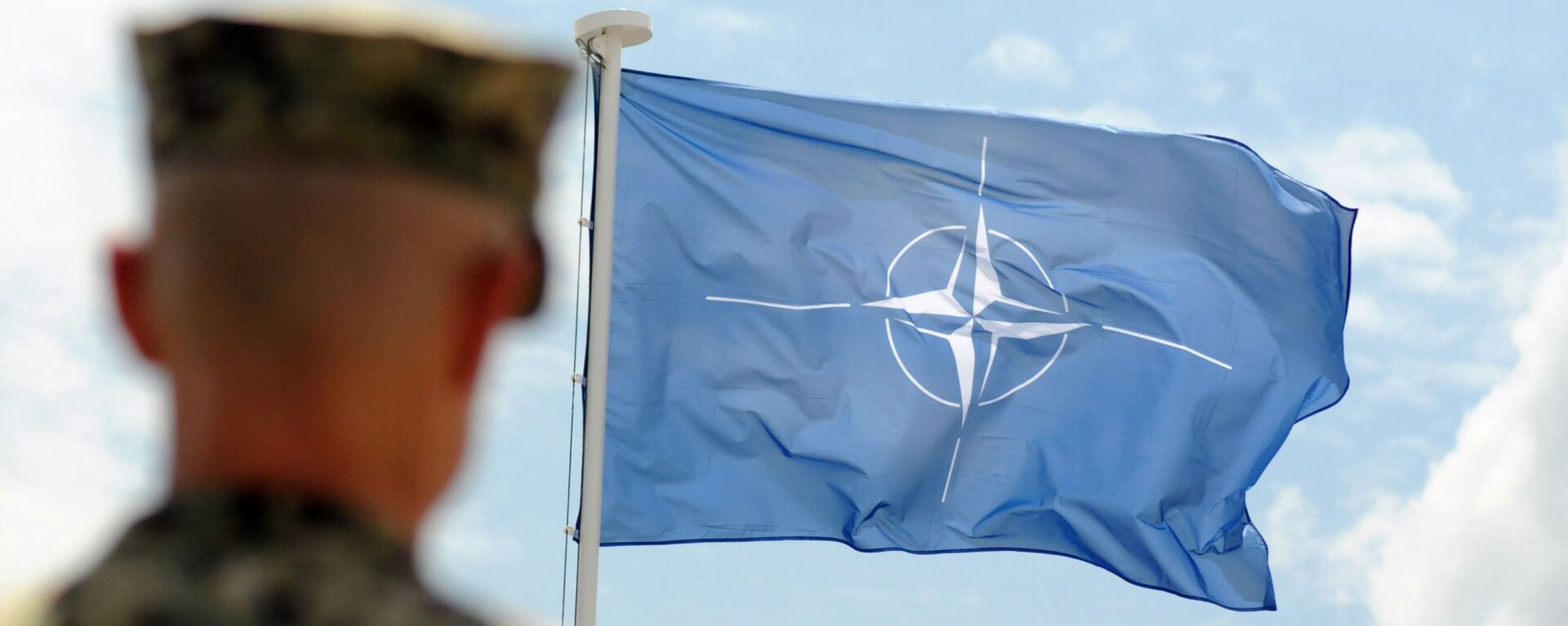 Военнослужащий НАТО на фоне флага НАТО в Косово - Sputnik 日本, 1920, 17.12.2021