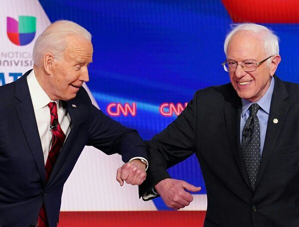 2020年3月15日、米ワシントンで開かれた第11回民主党大統領候補討論会で、肘を交わして挨拶する民主党のバイデン前副大統領（左）とサンダース上院議員（右） - Sputnik 日本