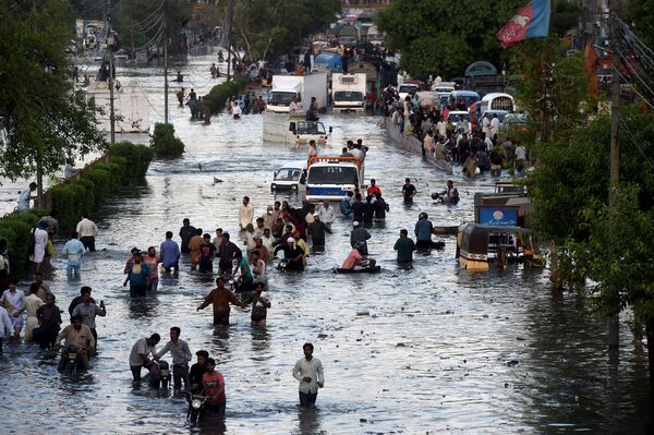 7月27日、パキスタンのカラチでモンスーンの大雨の後、冠水した道路を渡って通勤する人々 - Sputnik 日本