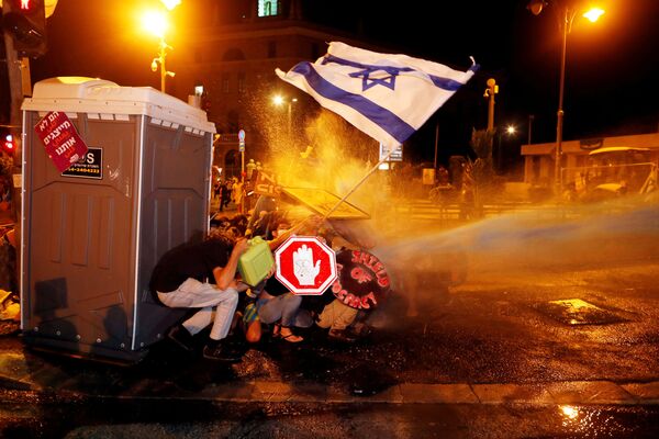7月26日、 イスラエルのエルサレムで行われたネタニヤフ首相の辞任を求める抗議デモで、警察の放水銃を回避するデモ隊 - Sputnik 日本