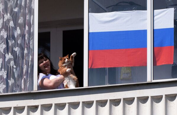 ロシア、クラスノヤルスク地方でロシアの日、窓から顔を出して音楽アンサンブルを眺める飼い主と猫 - Sputnik 日本