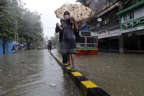 8月4日、インドのムンバイで、雨季の大雨で冠水した道路を歩く地元住民 - Sputnik 日本