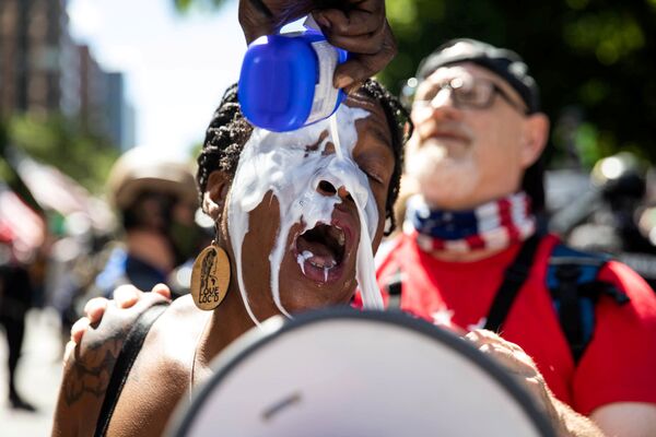 8月22日、米オレゴン州ポートランドで行われた人種差別反対デモで、牛乳で目を洗う女性 - Sputnik 日本