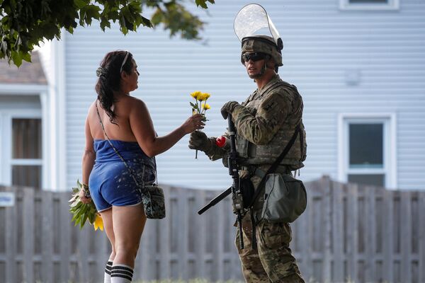 8月28日、米ウィスコンシン州ケノーシャで行われた警官の黒人男性銃撃事件をめぐる抗議デモで、動員された州兵に花束を渡す女性 - Sputnik 日本