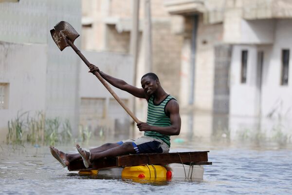 9月8日、セネガルのクール・マサールで、洪水によって浸水した通りをスコップで漕ぐ男性 - Sputnik 日本