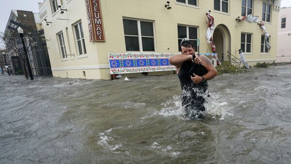 9月16日、米フロリダ州ペンサコーラで、冠水した街を歩く男性 - Sputnik 日本