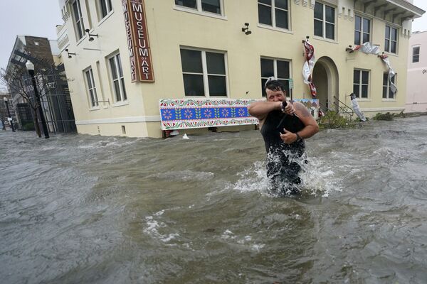9月16日、米フロリダ州ペンサコーラで、冠水した街を歩く男性 - Sputnik 日本