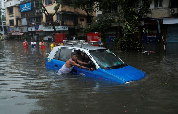 9月23日、インドのムンバイで大雨により水没した車を押す男性 - Sputnik 日本
