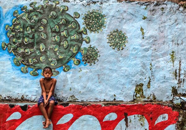 9月27日、インドネシアの西ジャワ州で、コロナウイルスが描かれた壁の前に座る少年 - Sputnik 日本