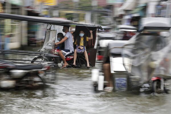 台風モラベが通過したフィリピン北部のパンパンガ州で、冠水した道路をオートバイで走る住民 - Sputnik 日本