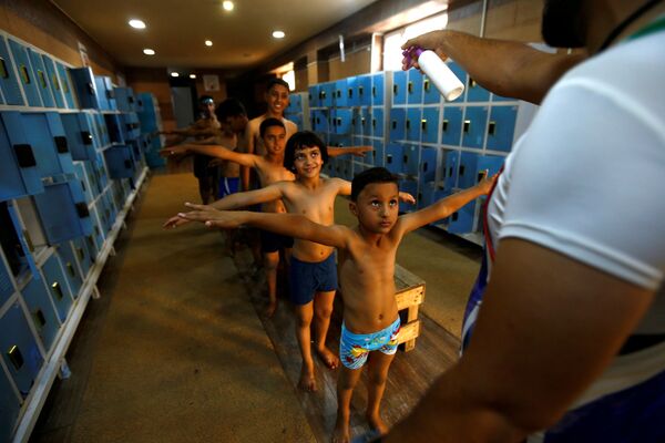 イラク中部カルバラーで、プールに入る前に子どもたちに消毒スプレーをかける男性 - Sputnik 日本