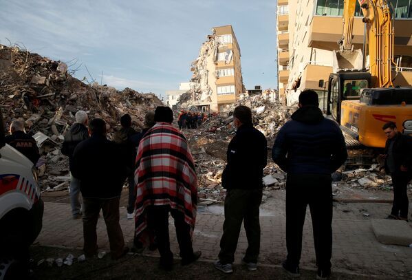トルコ西部のイズミルで11月3日、建物の崩壊現場で行われる救助活動を見守る地元住民ら - Sputnik 日本