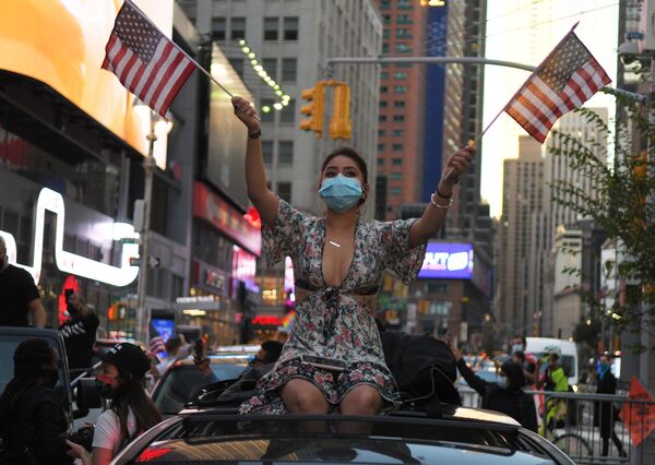バイデン氏の当選確実の報道を受け、ニューヨークの路上で旗を振る女性 - Sputnik 日本