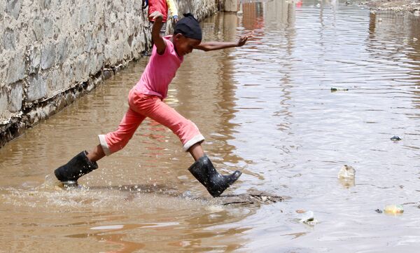 ケニアのナクル郡で、湖が溢水した影響で冠水した道をスキップする子ども - Sputnik 日本
