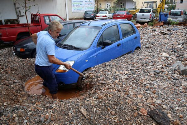 ギリシャのクレタ島で、大雨の後車を掘り起こす男性 - Sputnik 日本