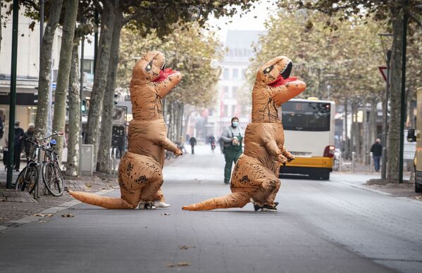 カーニバルが中止になったドイツのマインツで、恐竜の格好をして街を歩くパフォーマー - Sputnik 日本