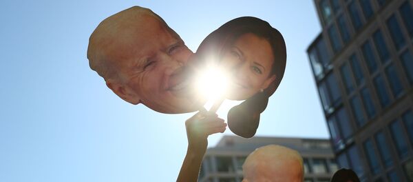 A supporter holds up cutouts of Joe Biden and Kamala Harris near the White House - Sputnik 日本