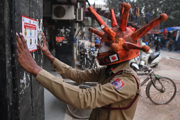  インド首都ニューデリーで、コロナウイルスの形をしたヘルメットを被って啓発ポスターを貼るボランティア - Sputnik 日本