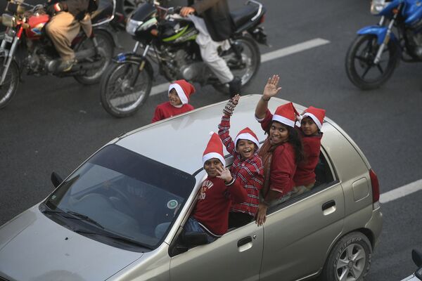 パキスタンの首都イスラマバードで、サンタクロースの帽子を被って車から顔を出す子どもたち - Sputnik 日本