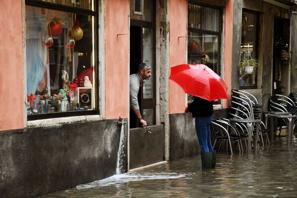 高潮で冠水した道路脇の店で、店内への水の浸入を防ぐ店主 - Sputnik 日本