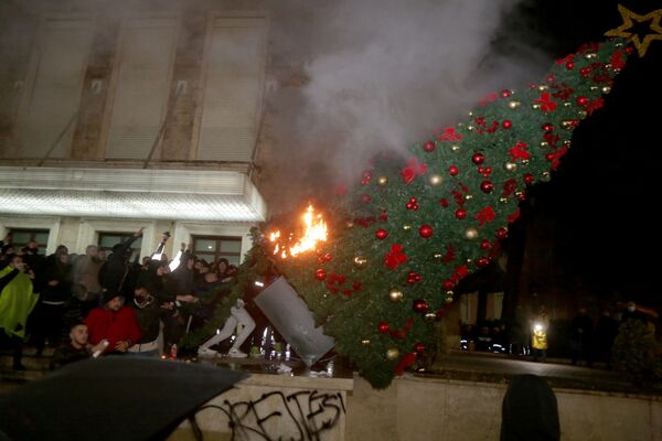 アルバニア首都ティラナで行われた、外出禁止令を破った男性が警官に射殺されたことに対する抗議デモで、クリスマスツリーを燃やすデモ隊 - Sputnik 日本
