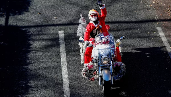 Мужчина в костюме Санта-Клауса на мотоцикле Harley Davidson во время рождественского парада в Токио