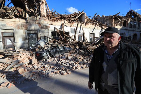 中部・ペトリニャで崩壊した建物のそばを歩く男性 - Sputnik 日本