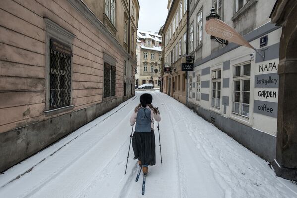 チェコ・プラハで、雪が積もった通りでスキーをする女性 - Sputnik 日本