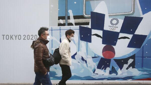 Люди проходят мимо плакатов, рекламирующих Олимпийские игры в Токио - Sputnik 日本