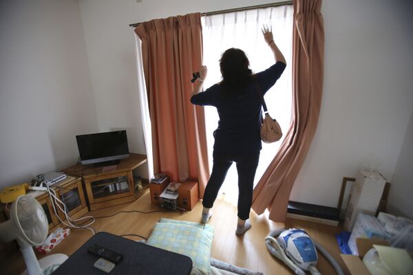 福島県双葉郡楢葉町で、約2ヶ月ぶりに帰宅した自宅のカーテンを開ける女性（2015年9月4日撮影） - Sputnik 日本