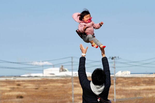 福島県双葉郡浪江町の海岸で娘を抱きあげる男性（2021年3月11日） - Sputnik 日本