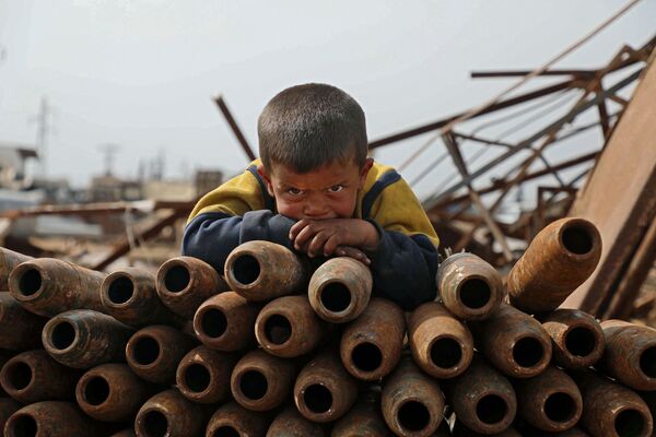 シリア・イドリブ県の金属くず置き場で、老朽化した砲弾の山の上に寝そべる子ども - Sputnik 日本