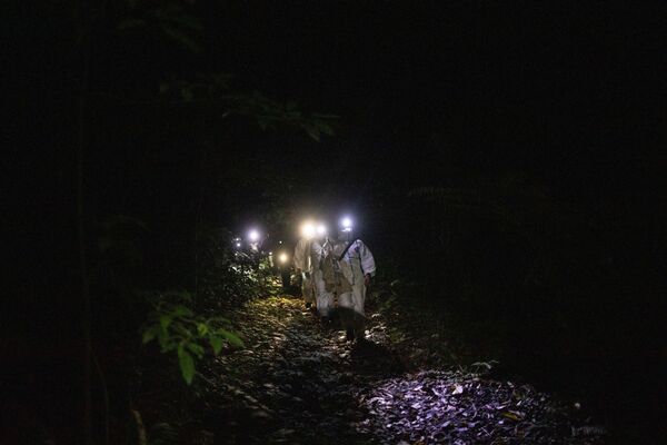 フィリピン・ラグナ州のマキリン山の麓で、捕獲したコウモリを入れた布袋を持つ生態学者のカーク・タレイ氏ら - Sputnik 日本