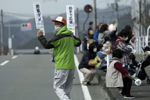 福島県楢葉町で行われた聖火リレーの第1区間周辺で、観客にプラカードで感染対策を促す地元スタッフ - Sputnik 日本