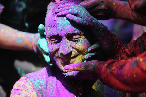 インド・ジャンムーで行われた「ホーリー祭」で、顔にカラーパウダーを塗られる参加者 - Sputnik 日本