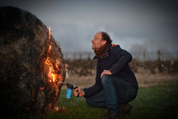 フランス・トゥーレーヌ地方にあるヴーヴレのブドウ畑で、霜害を防ぐため藁に火をつけるワイン農家 - Sputnik 日本