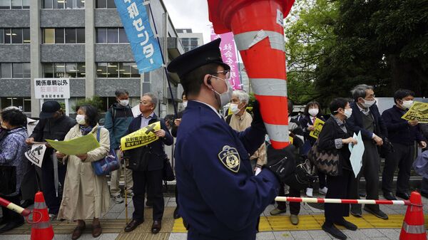 福島第一原発の処理水の海洋放出が決定したことを受け、東京都千代田区の首相官邸前で行われた抗議デモで、コーンを持ち上げる警察官 - Sputnik 日本