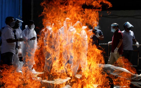 インド・ニューデリーの火葬場で、新型コロナウイルスで死亡した男性の葬儀に防護服を着て参列する親族ら - Sputnik 日本