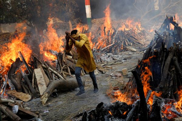インド・ニューデリーで、新型コロナに感染し死亡した人を火葬中の火葬場を歩く男性 - Sputnik 日本
