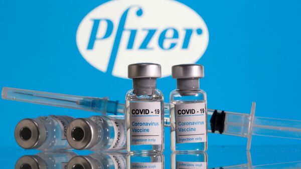 Vials labelled COVID-19 Coronavirus Vaccine and a syringe are seen in front of the Pfizer logo in this illustration taken February 9, 2021 - Sputnik 日本