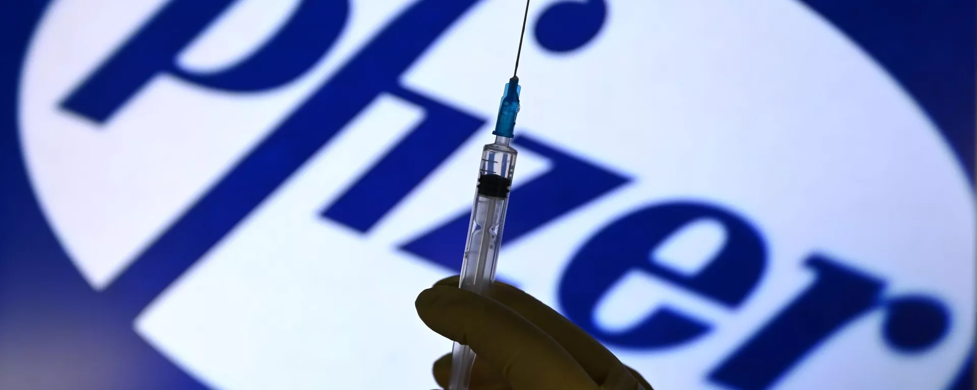 A syringe in front of the Pfizer logo. - Sputnik 日本, 1920, 13.01.2022