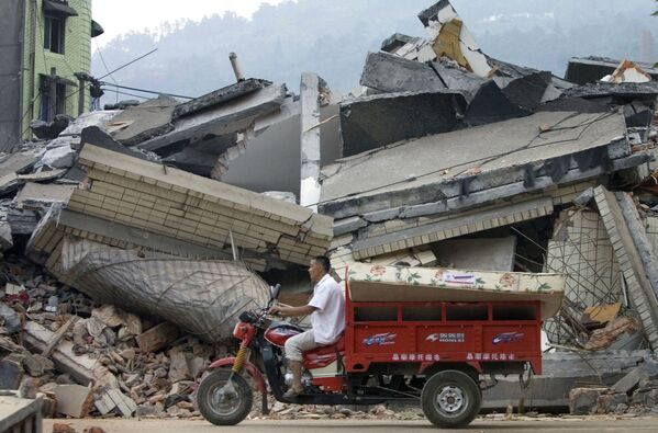 四川省漢旺で、地震で倒壊した建物の前をスクーターで通り過ぎる住民 - Sputnik 日本