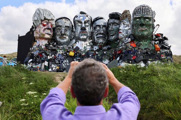 英イングランド・コーンウォールで、G7サミット開催前に電子廃棄物で作られたG7の首脳らのアート「Mount Recyclemore」を撮影する男性 - Sputnik 日本