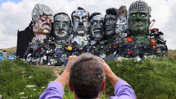英イングランド・コーンウォールで、G7サミット開催前に電子廃棄物で作られたG7の首脳らを描いたアート「Mount Recyclemore」を撮影する男性 - Sputnik 日本