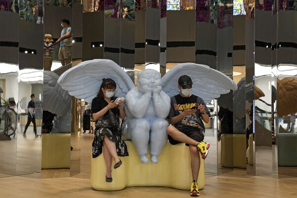 中国・北京のショッピングモールで、天使の像に座ってスマートフォンを見る男女 - Sputnik 日本