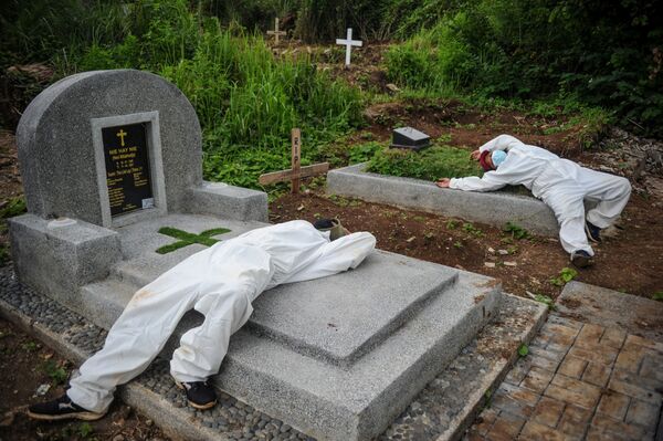 インドネシア・西ジャワ州バンドンで、新型コロナウイルスによる死亡者を埋葬した後、防護服を着たまま休憩する作業員ら - Sputnik 日本