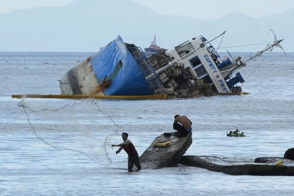 フィリピン・マニラ沖で、座礁した船の近くで網を張る漁師 - Sputnik 日本